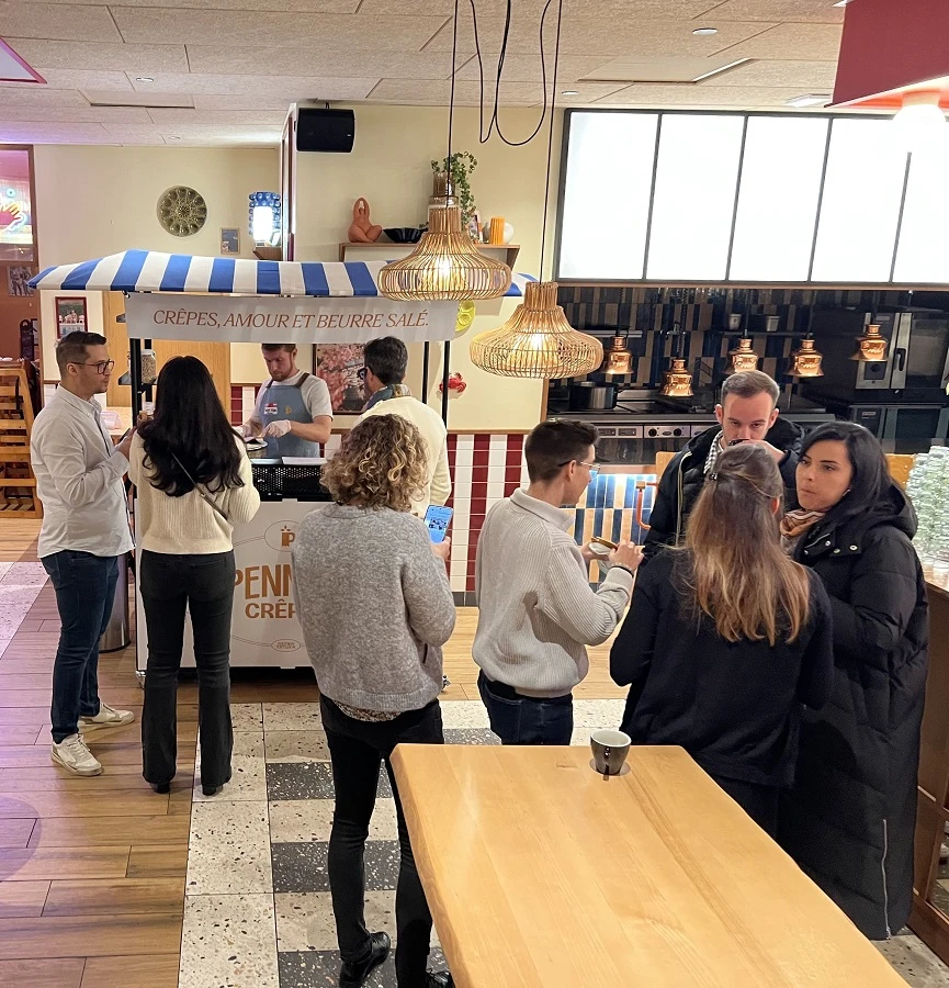 Le chariot de penn ar crêpes est installé dans un restaurant pour une réunion d'entrepreneurs. Des chefs d'entreprise sont debout devant le chariot à déguster des crêpes